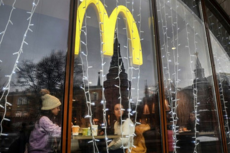 People look out of the window of a McDonald's restaurant as the towers of the Kremlin reflect in it in Moscow on January 30, 2020