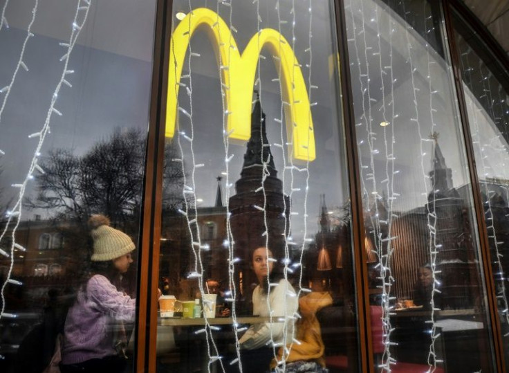 People look out of the window of a McDonald's restaurant as the towers of the Kremlin reflect in it in Moscow on January 30, 2020