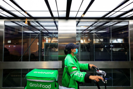 A driver working for the ridesharing company Grab holds a bicycle as she delivers food amid of the coronavirus disease (COVID-19) pandemic in Jakarta, Indonesia, March 15, 2022. 