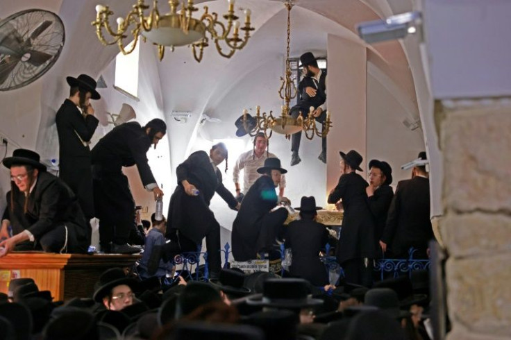 Ultra-Orthodox Jews climb over a fence to reach the tomb of Rabbi Shimon Bar Yochai, a year after 45 people were crushed to death at the Mount Meron site