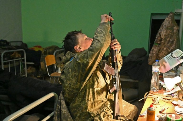 A Ukranian soldier cleans his weapon as he rests in a hideout shelter along the front line near Ukraine's second largest city Kharkiv on April 17, 2022