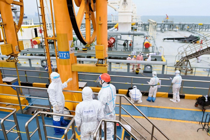 Immigration inspection officers in protective suits check a tanker carrying imported crude oil at the port in Qingdao, Shandong province, China May 9, 2022. China Daily via REUTERS