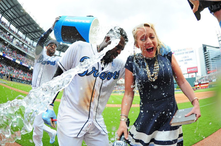 Brandon Phillips #4 of the Atlanta Braves is doused by Matt Kemp #27 with a water cooler, along with Braves reporter Kelsey Wingert