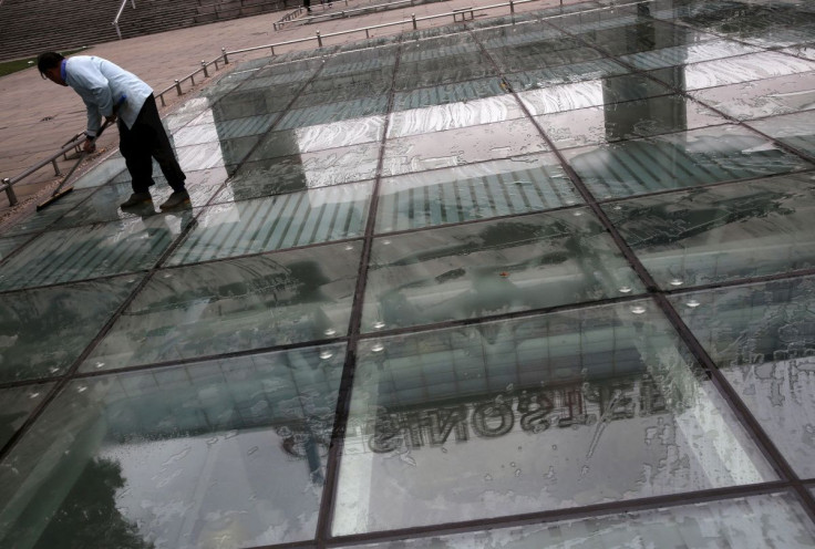 A worker cleans a glass floor reflecting Sinosteel's logo,  in front of Sinosteel'sheadquarter building in Beijing, China, October 21, 2015.  