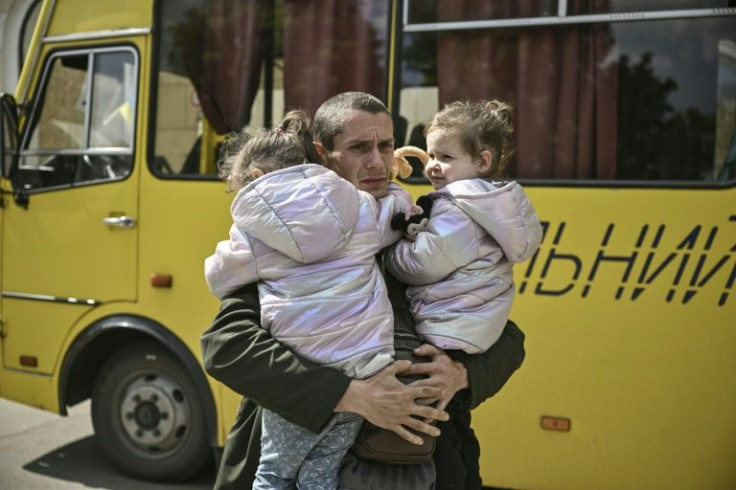 Dmytro Mosur, 32, who lost his wife during shelling in nearby Severodonetsk on May 17, holds his two-year-old twin daughters as they wait to be evacuated from the city of Lysychansâk, eastern Ukraine