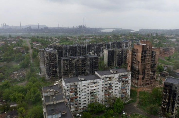 Charred residential buildings in Mariupol with the Azovstal steel plant in the background