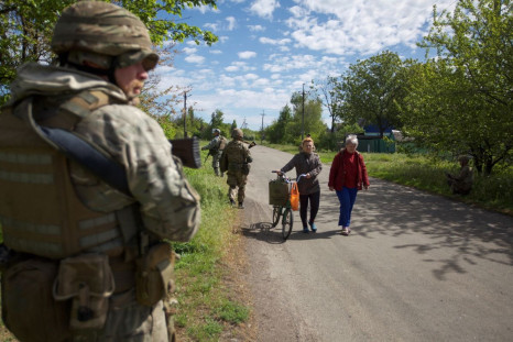 Local women walk along a street while Ukrainian servicemen patrol an area, as Russia's attack on Ukraine continues, in the town of Kurakhove, in Donetsk region, Ukraine May 20, 2022. Picture taken May 20, 2022.  