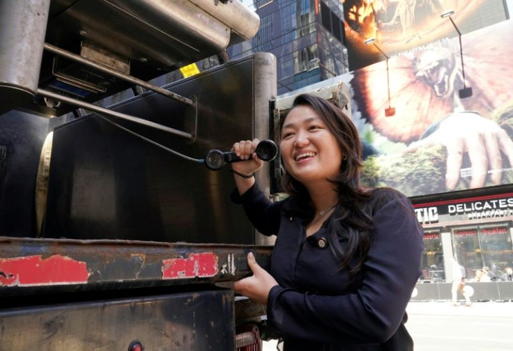 Manhattan council member Jilie Won poses briefly with the last payphone in New York before the booth was hoisted on to a waiting truck