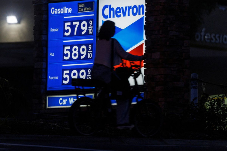 A woman rides an electric bike past a gas station as current gasoline prices continues to climb close to record setting territory in Encinitas, California, U.S., May 9, 2022.  