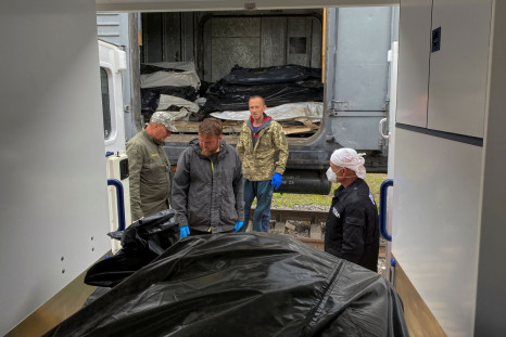 Ritual workers stand next to bodies of killed Russian soldiers before loading them to a refrigerated rail car, as Russia's attack on Ukraine continues, at a compound of a morgue in Kharkiv, Ukraine May 22, 2022.  