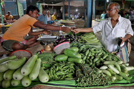 Nikhil Kumar Mondal, 65, a retired school headmaster, buys vegetables from a vendor at a market on the outskirts of Kolkata, India, May 20, 2022. 