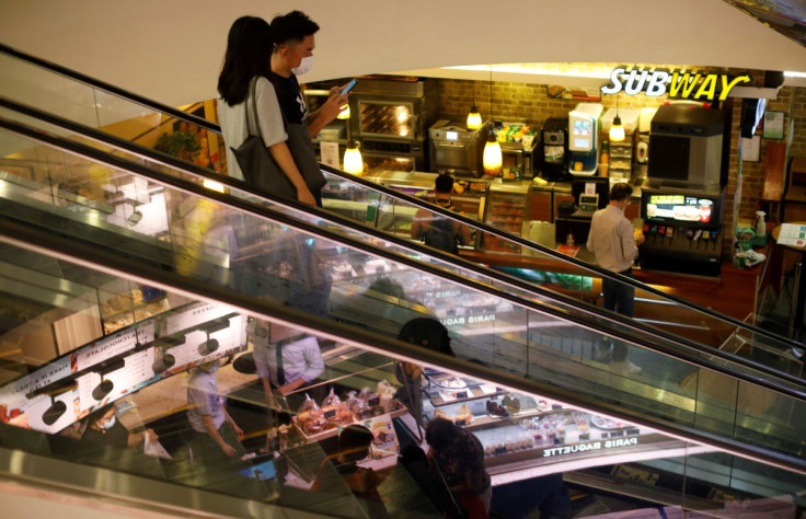 People wearing protective face masks ride an escalator at a shopping mall, amid the coronavirus disease (COVID-19) outbreak, in Singapore July 14, 2020.