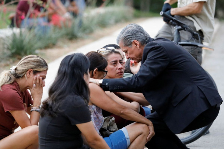 A priest comforts people as they react outside the Ssgt Willie de Leon Civic Center, where students had been transported from Robb Elementary School after a shooting, in Uvalde, Texas, U.S. May 24, 2022.  