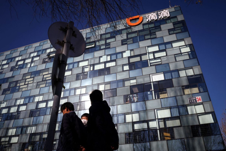 People walk past the headquarters of the Chinese ride-hailing service Didi in Beijing, China, December 3, 2021. 