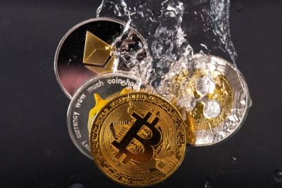 Souvenir tokens representing cryptocurrency networks Bitcoin, Ethereum, Dogecoin and Ripple plunge into water in this illustration taken May 17, 2022. 