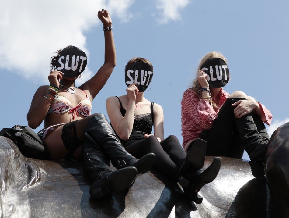 Women sit on a lion in Trafalgar Square during a rally after SlutWalk in London