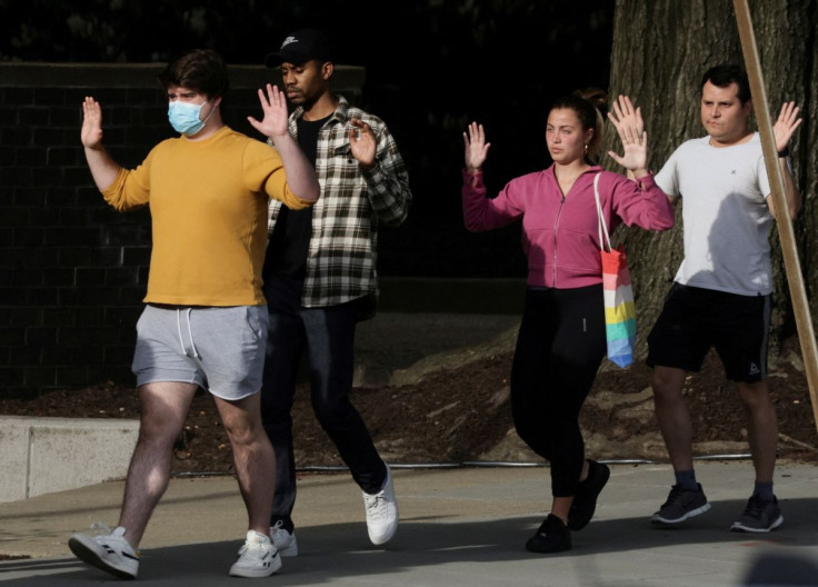 Local residents hold their hands in the air as they are evacuated to safety by police at the scene of a reported shooting and active shooter near Edmund Burke Middle School in the Cleveland Park neighborhood of Northwest Washington, U.S., April 22, 2022. 