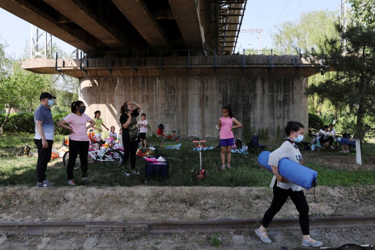 People have picnics under a railway bridge at a park, amid the coronavirus disease (COVID-19) outbreak, in Beijing, China May 21, 2022. Picture taken May 21, 2022. 
