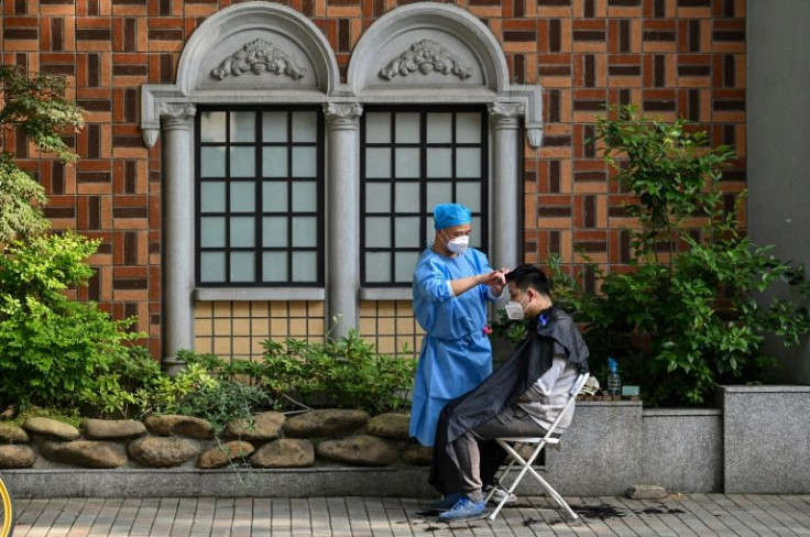 A barber in protective gear gave customers haircuts in a makeshift roadside salon in Shanghai