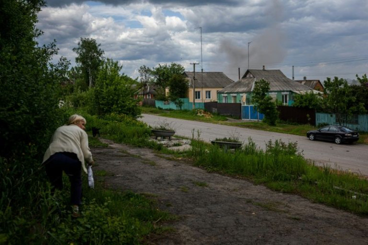 A resident rushes to safety before Russian shells start slamming into her village near Kharkiv