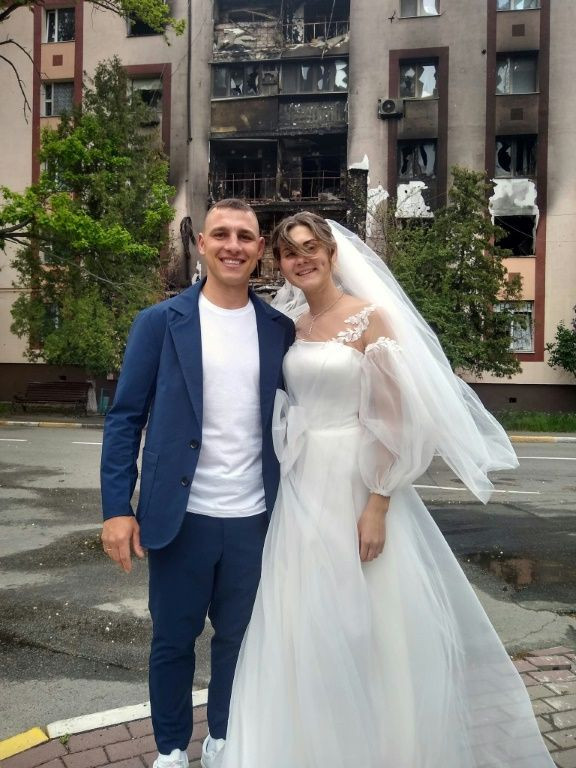 Mykhaylo Dewberry and his bride Anastasia posed, she in a long white dress and he in a bright blue suit, as passing drivers honked their horns