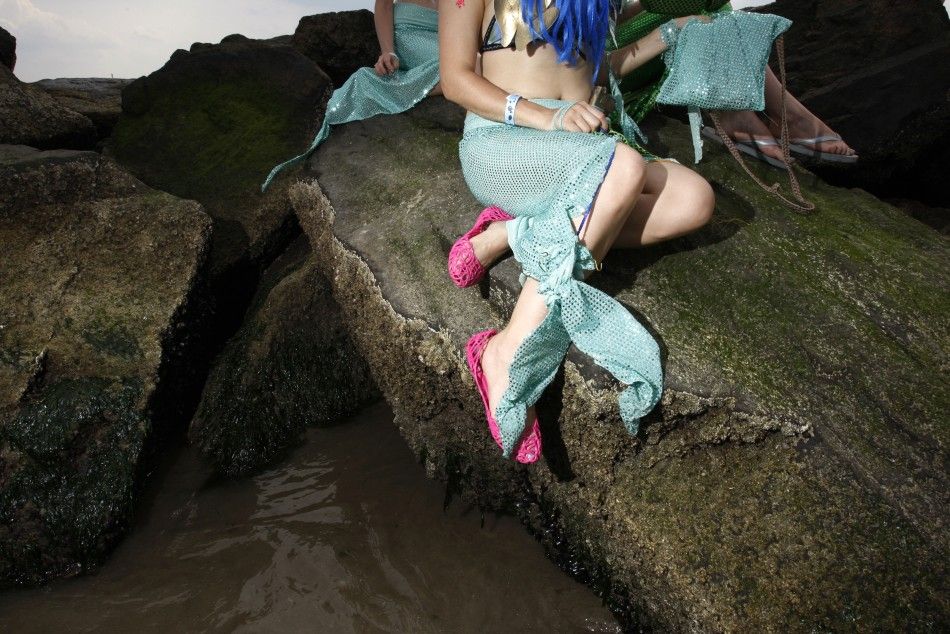 Women dressed as mermaids perch on a rock after the Mermaid Parade at Coney Island in the Brooklyn section of New York