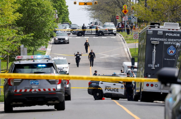 Police officers work at the scene where police shot and injured a suspect who was walking down a city street carrying a gun, as four nearby schools were placed on lockdown, in Toronto, Ontario, Canada, May 26, 2022.