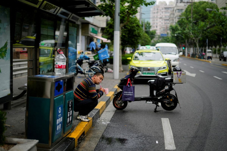 A delivery worker, who says he is living at a bus stop because he has been unable to return home for weeks due to the lockdown, brushes his teeth on a street, amid the coronavirus disease (COVID-19) pandemic, in Shanghai, China, May 12, 2022.