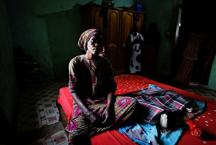 Anta Ba, a mother who lost one of her triplets, sits on her bed beside her son and daughter who were discharged hours before a fire at the neonatal unit of Mame Abdou Aziz Sy Dabakh hospital in Tivaouane, that killed eleven newborn babies, at her house in