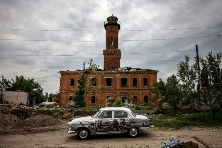 A man drives a GAZ-21 Volga car past a damaged building in Kharkiv, eastern Ukraine.