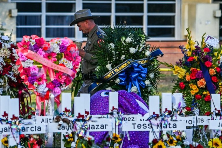 A police officer stands near the makeshift memorial for the shooting victims outside Robb Elementary School in Uvalde, Texas, on May 28, 2022