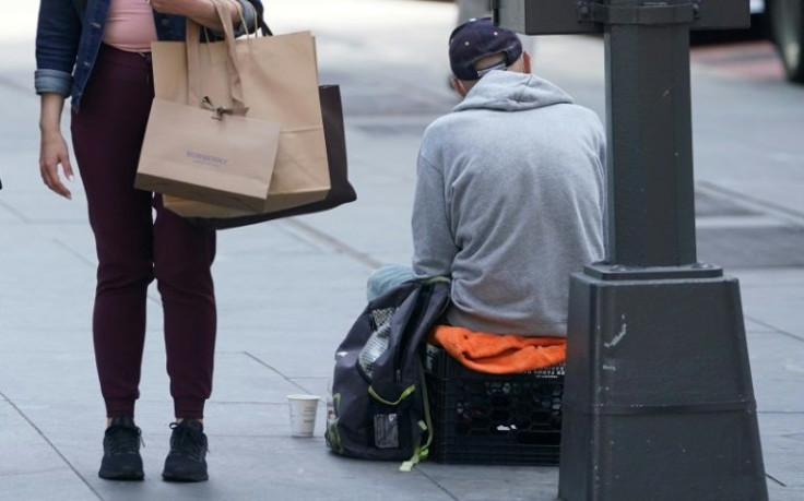 A pedestrian passes a man seeking handouts on New York's Fifth Avenue; despite recent wage increases by some employers, stark income inequalities remain