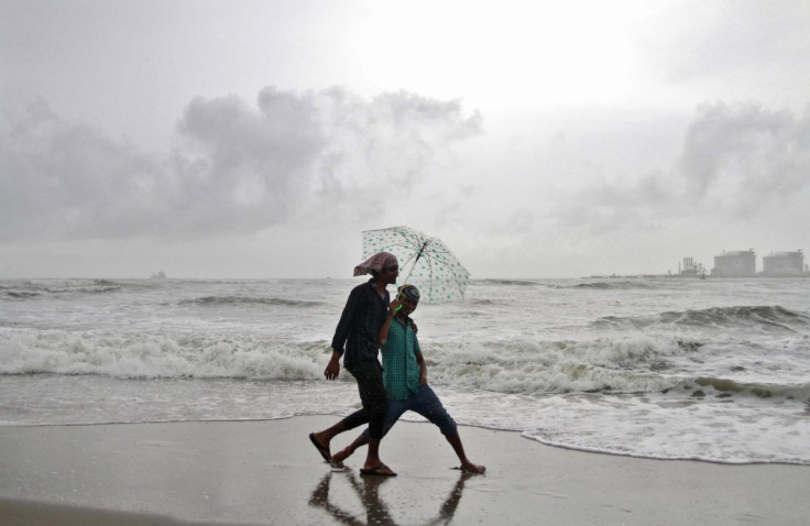 FILE PHOTO; Beachgoers react to the camera while holding an umbrella as it drizzles at the Fort Kochi beach in the southern Indian city of Kochi June 6, 2014. 