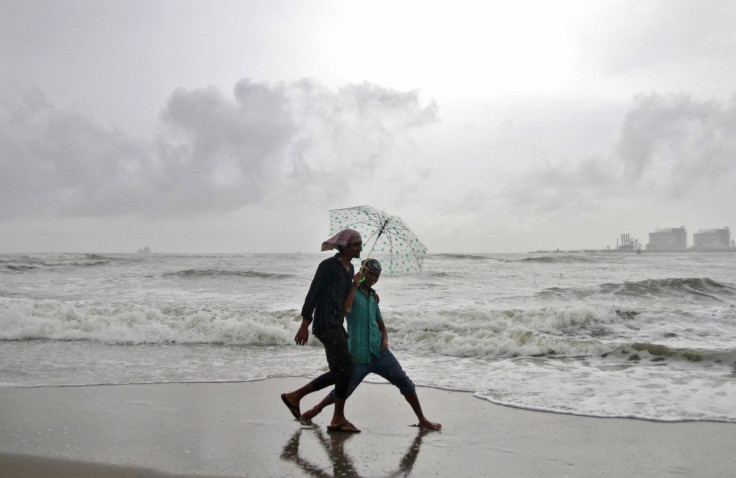 FILE PHOTO; Beachgoers react to the camera while holding an umbrella as it drizzles at the Fort Kochi beach in the southern Indian city of Kochi June 6, 2014.