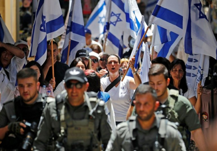Members of Israeli security accompany Israelis lifting their national flag in Jerusalem's Old City on May 29, 2022