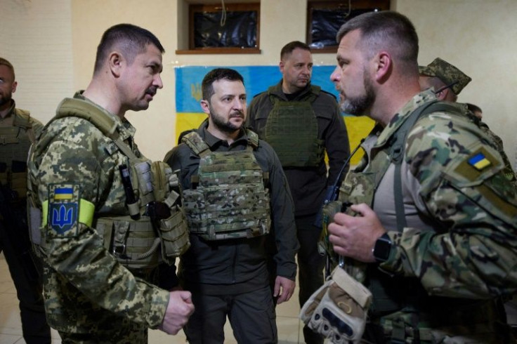 Ukrainian President Volodymyr Zelensky (C) talks with servicemen during his visit to the Kharkiv region