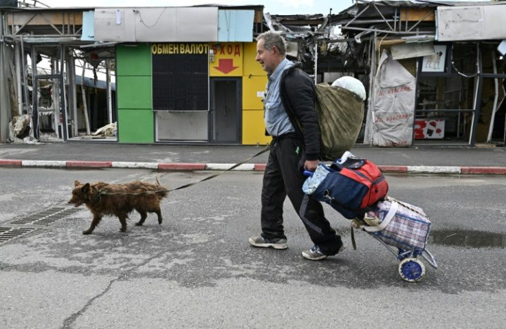 Kharkiv resident Oleksiy Malishenko, 73, walks with his dog past a market damaged by Russian shelling