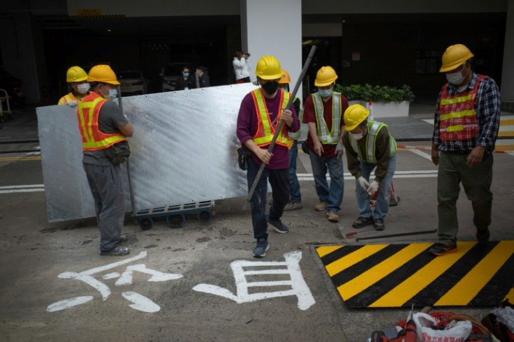 Construction workers stand next to Chinese characters reading "cold blood" as they use metal sheeting to cover up one of the last public tributes in Hong Kong to the deadly 1989 Tiananmen Square crackdown