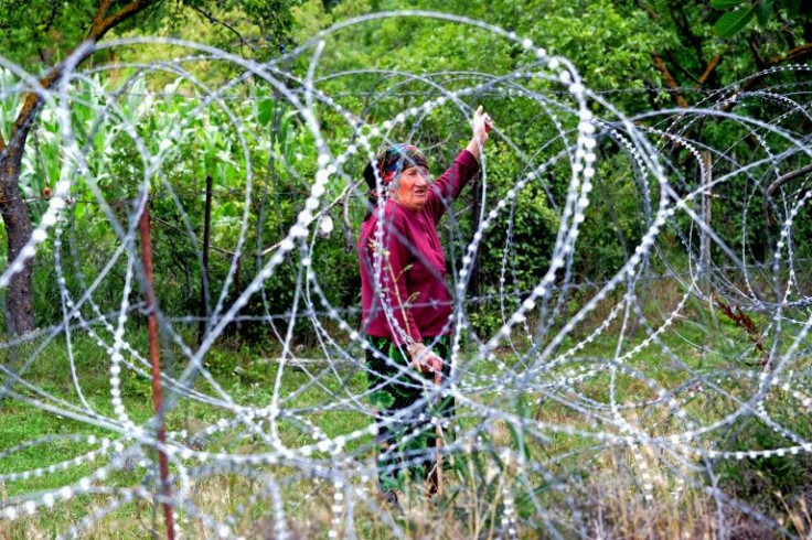 A woman looks through coils of razor wire that divide the breakaway territory of South Ossetia from Georgian-controlled land, in the Georgian village of Khurvaleti in July 2013