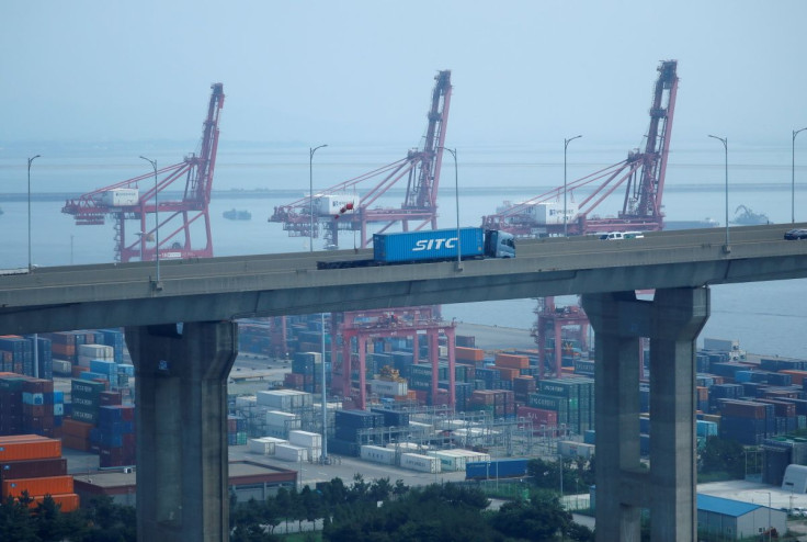A truck carrying a shipping container travels past cranes at Pyeongtaek port in Pyeongtaek, South Korea, July 9, 2020.    