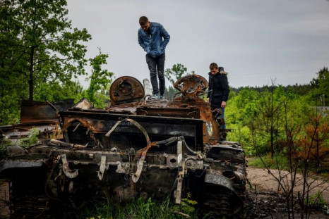 Local residents examine a destroyed Russian tank outside Kyiv, from which Russian forces retreated in late March to focus on the eastern Donbas region