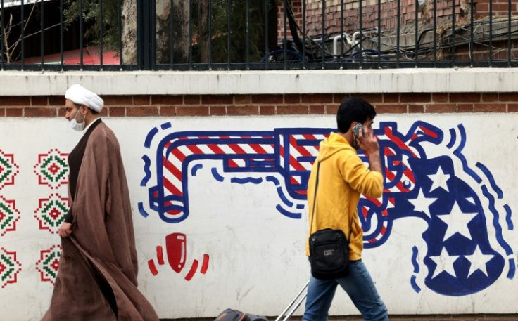 Iranians walk past an anti-US mural on a wall of the former United States embassy in the capital Tehran