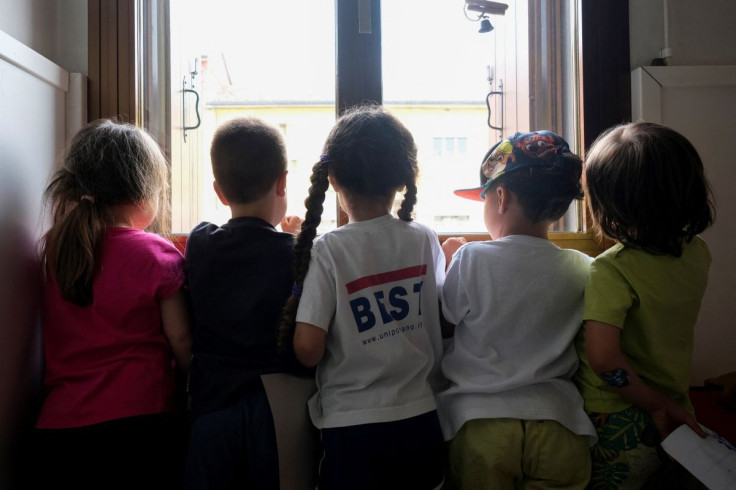 Children pose by a window inside a nursery of Cartigliano, a small town in northern Italy where firms are offering money to families to help them enrol children in nursery schools, Italy May 27, 2022.