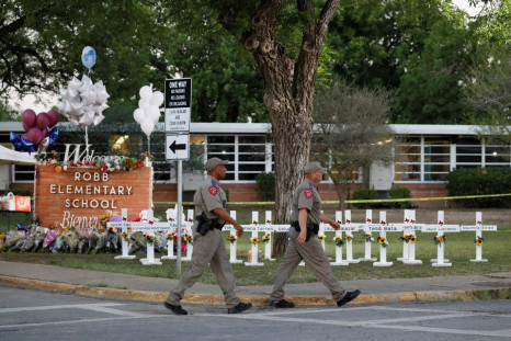 Texas Department of Public Safety officers walk past a memorial outside Robb Elementary school, after a gunman killed nineteen children and two teachers, in Uvalde, Texas, U.S. May 26, 2022. 