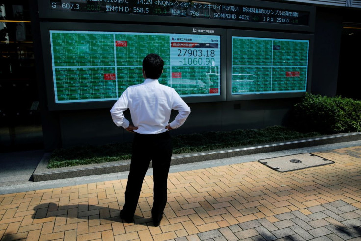 A man watches an electric board showing Nikkei index outside a brokerage at a business district in Tokyo, Japan, June 21, 2021.   