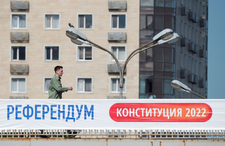 A man walks along a bridge near a banner informing of the upcoming referendum in Almaty, Kazakhstan June 1, 2022. A banner reads: "Referendum. Constitution 2022".