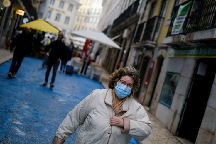 A woman wearing a protective mask walks, moments before a governmental news conference to announce new coronavirus disease (COVID-19) restrictions, in Lisbon, Portugal, December 21, 2021.