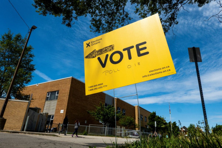 People walk by a vote sign near a polling station during Ontario?s provincial election in Hamilton, Ontario, Canada June 2, 2022.  