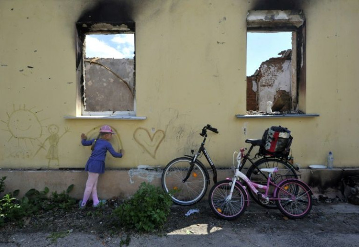 A young girl draws on the wall of a destroyed house in the Kyiv region