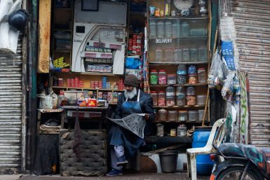 A man reads newspaper while selling betel leaves, known as pan, cigarettes and candies from a shop in Karachi, Pakistan, December 30, 2021. 